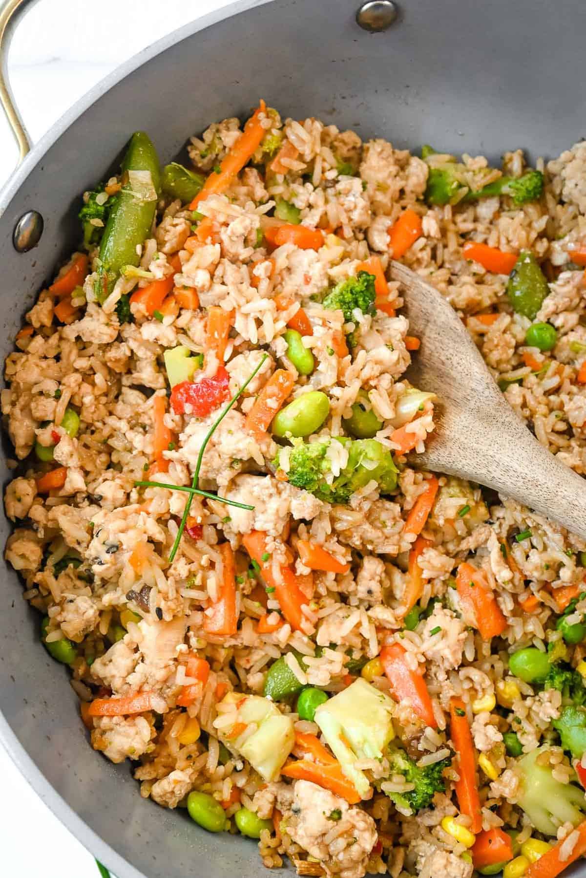 close up shot of ground chicken stir fry with a scoop of stir fry in a wooden spoon.