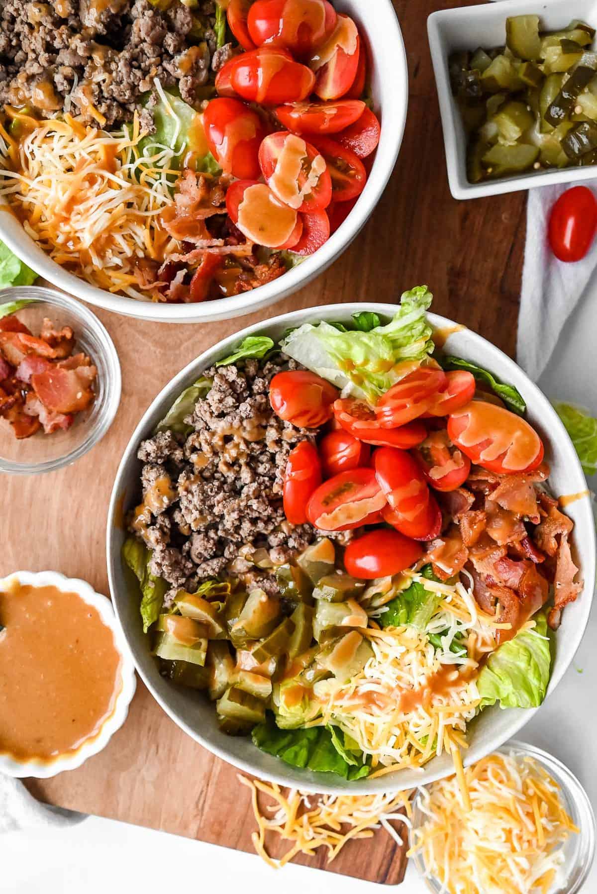 two burger bowls on a tray with special sauce for burgers.