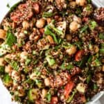 close up shot of spinach quinoa salad topped with fresh herbs and veggies.