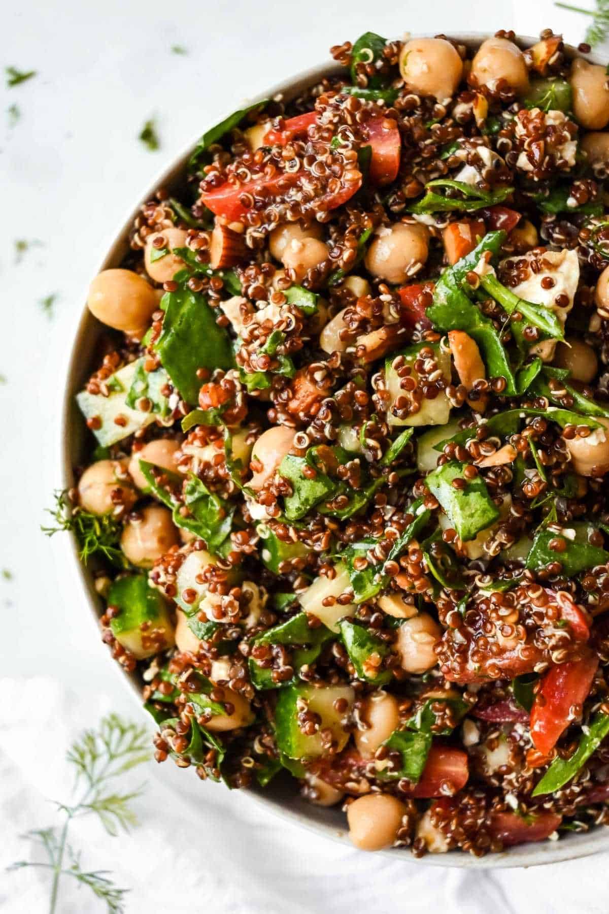 spinach quinoa salad in a bowl with fresh herbs.