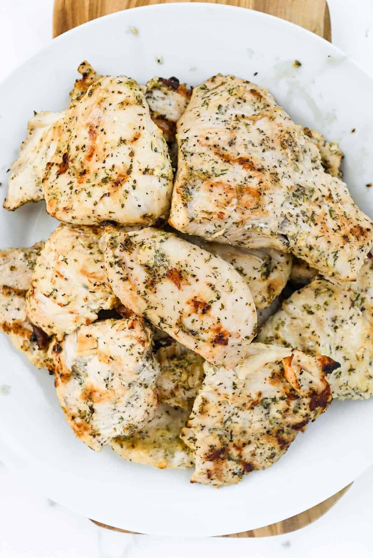 grilled chicken with seasoning on a white plate.