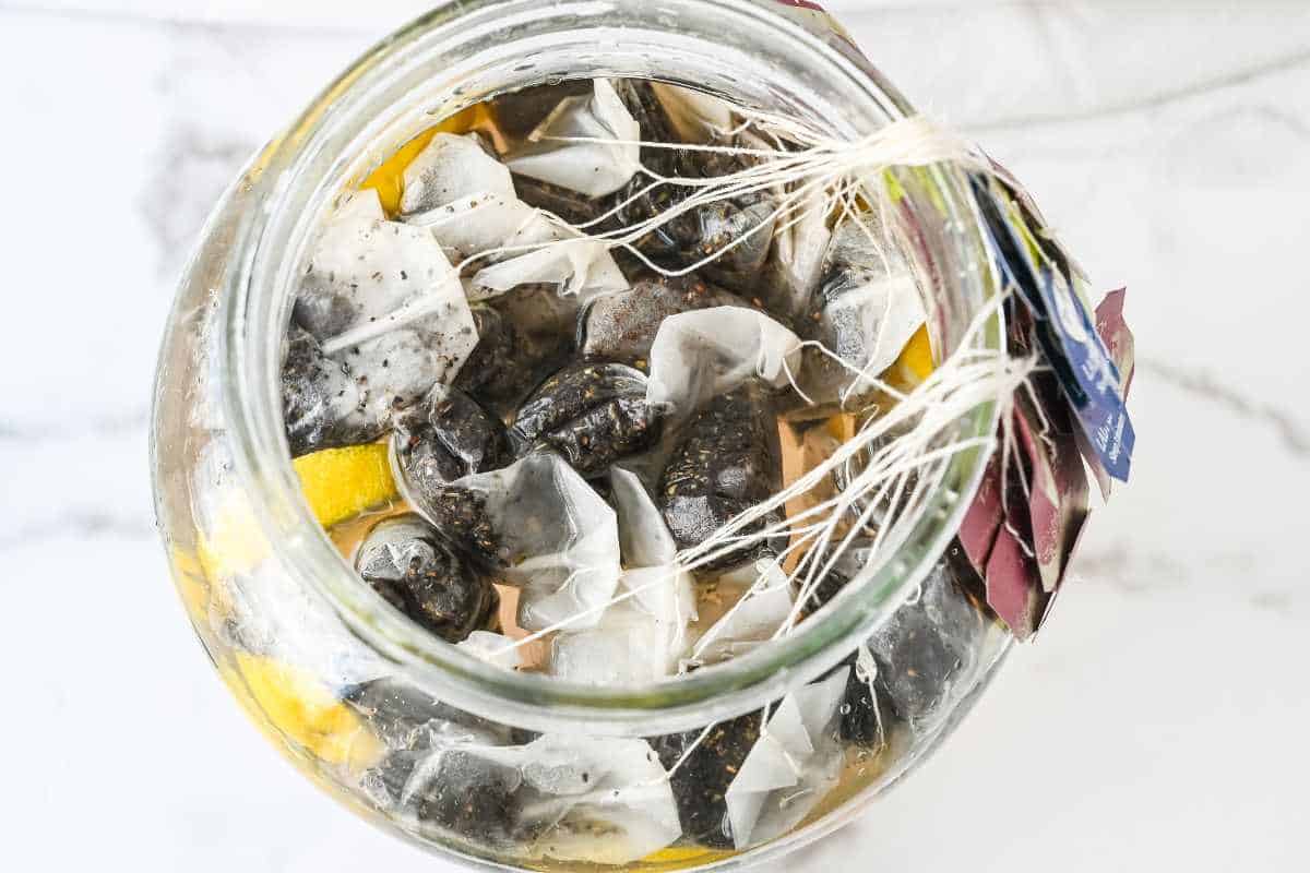 top down shot of tea bags and lemons submerged in water.