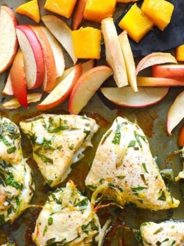 close up of baked chicken on a sheet pan with apples.
