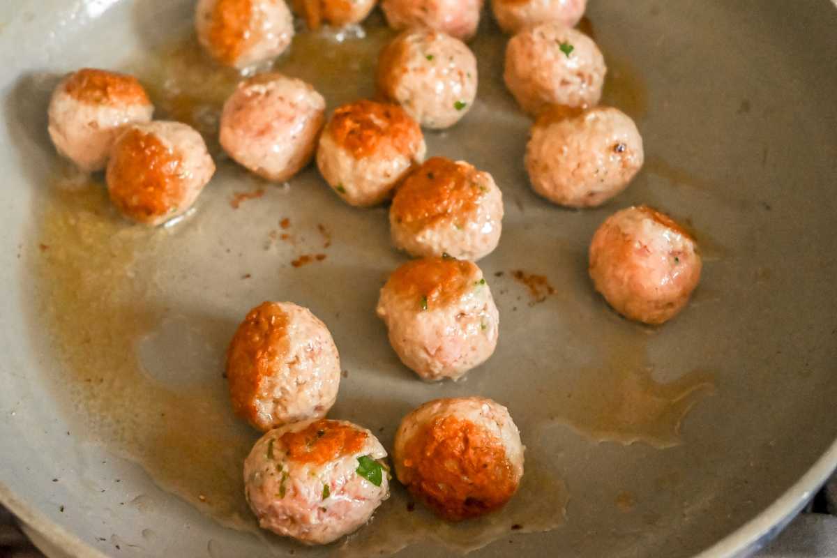 meatballs searing in a skillet.