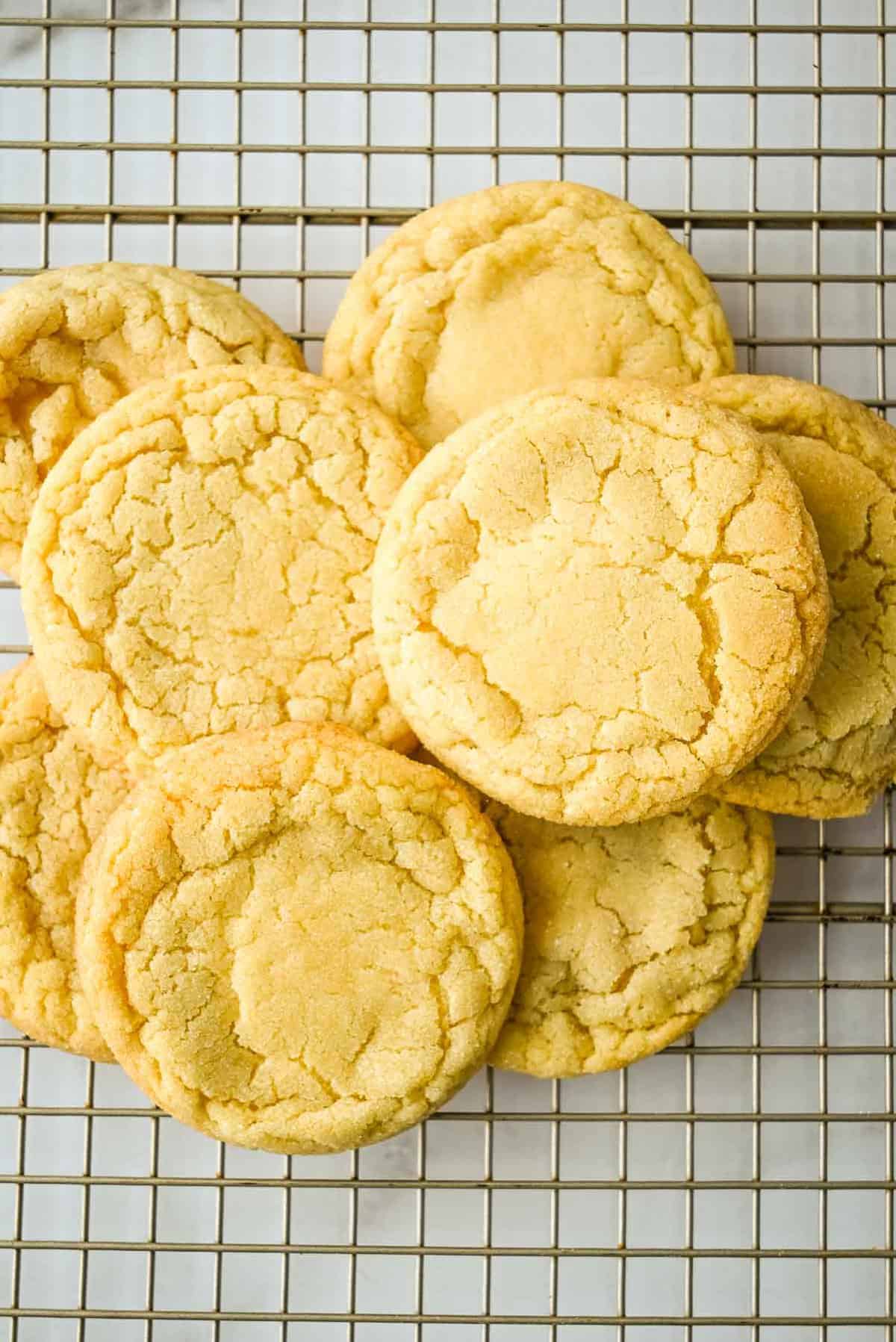 dairy free sugar cookies in a pile on a cooling rack.