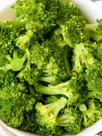 close up of steamed broccoli in a white dish.
