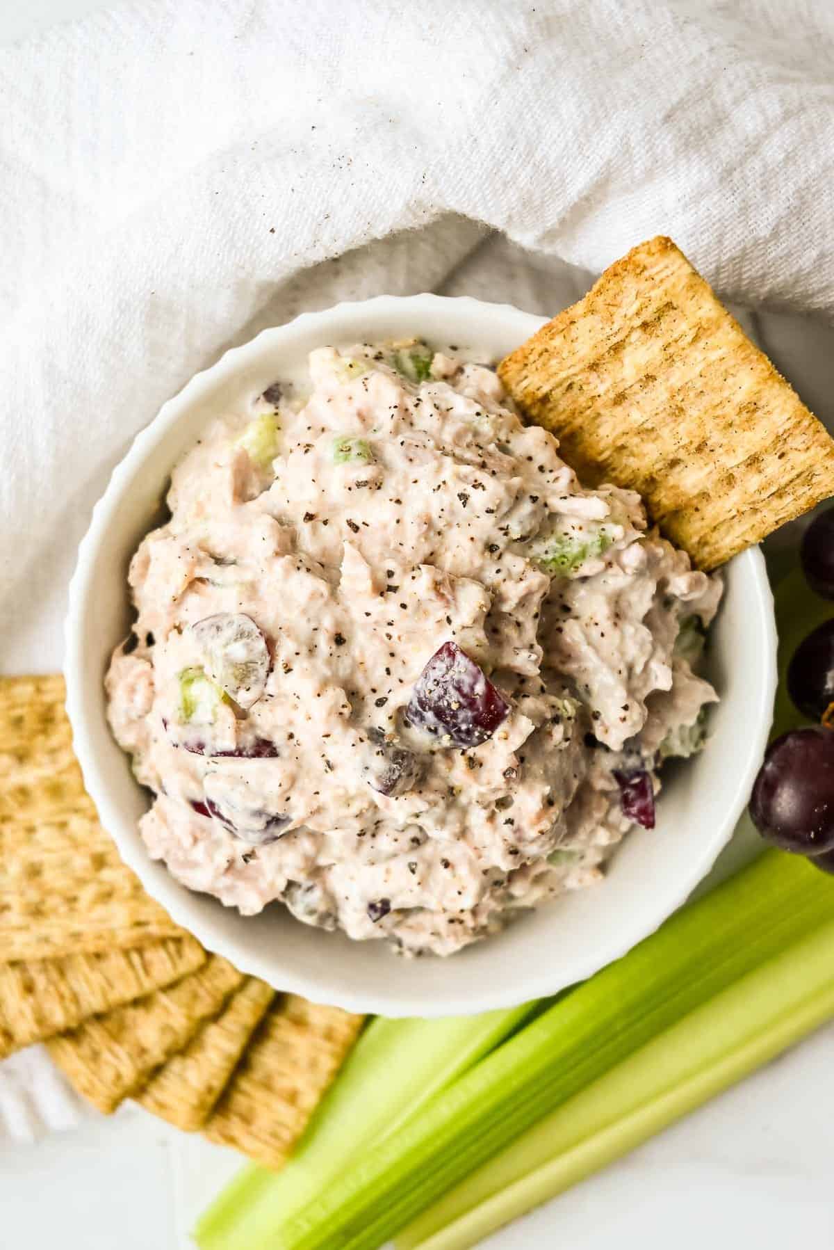 bowl of tuna salad with greek yogurt with crackers in a white bowl.