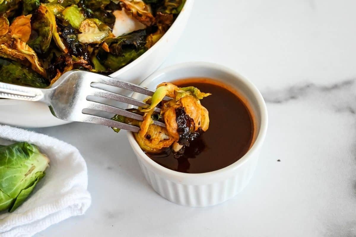 dipping brussel sprout in honey sriracha sauce
