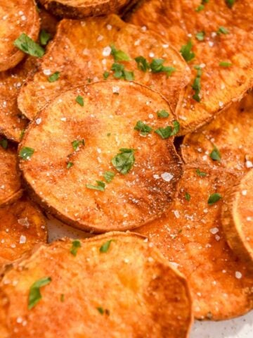 close up photo of air fryer sweet potato rounds topped with parsley and salt.
