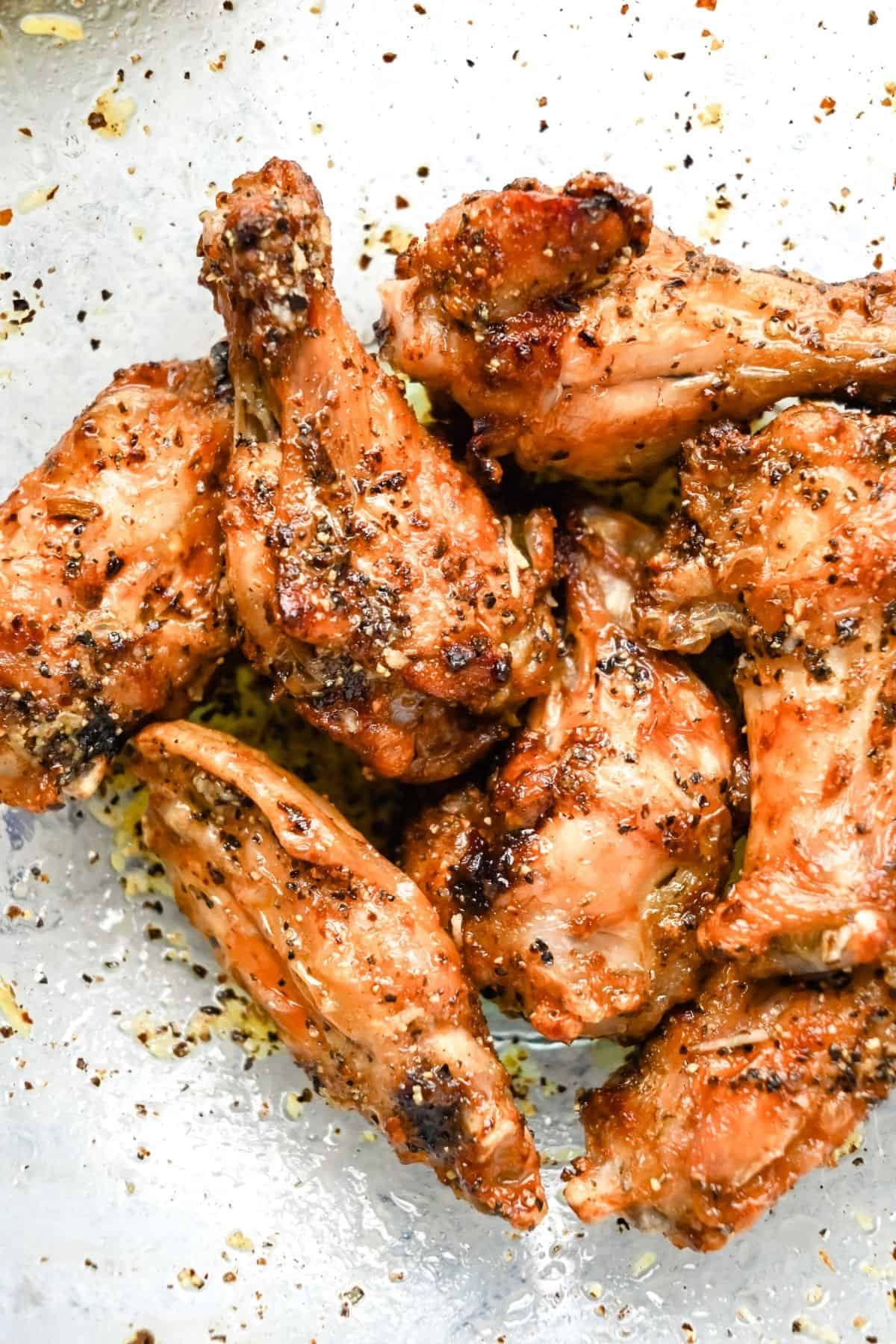 air fryer lemon pepper wings with seasoning in a bowl