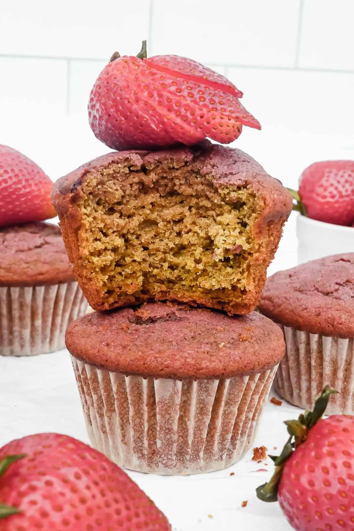 bite shot of inside of strawberry yogurt muffin on top of a muffin and topped with a strawberry.