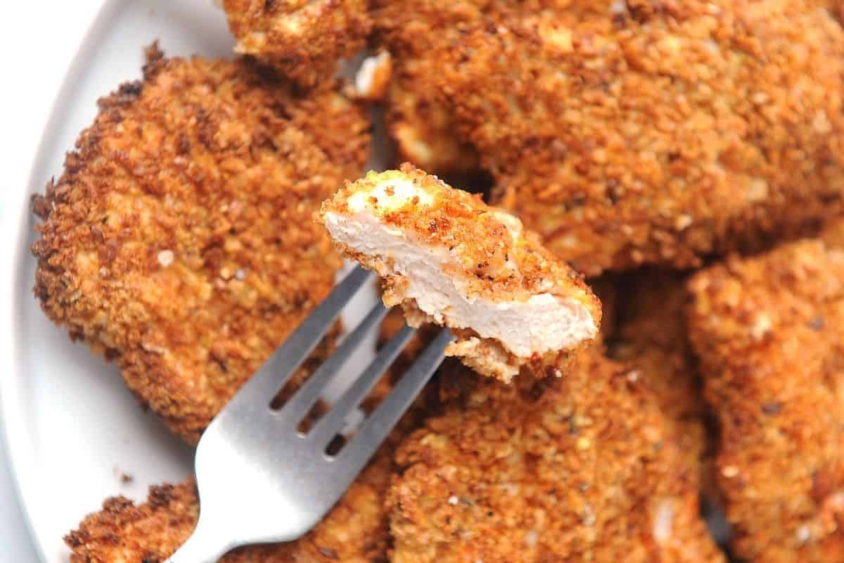 cut piece of juicy breaded chicken on a fork.
