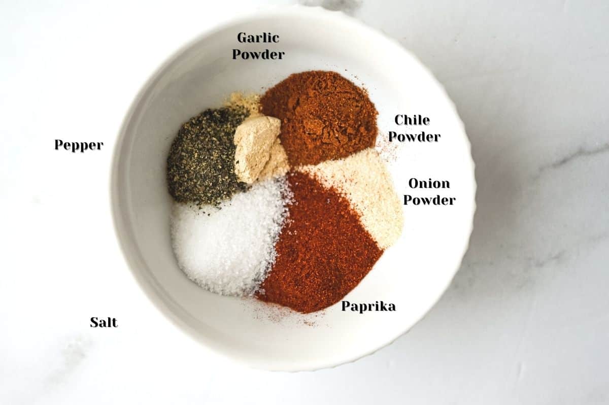 BBQ dry rub seasoning ingredients in a white bowl on a white background.