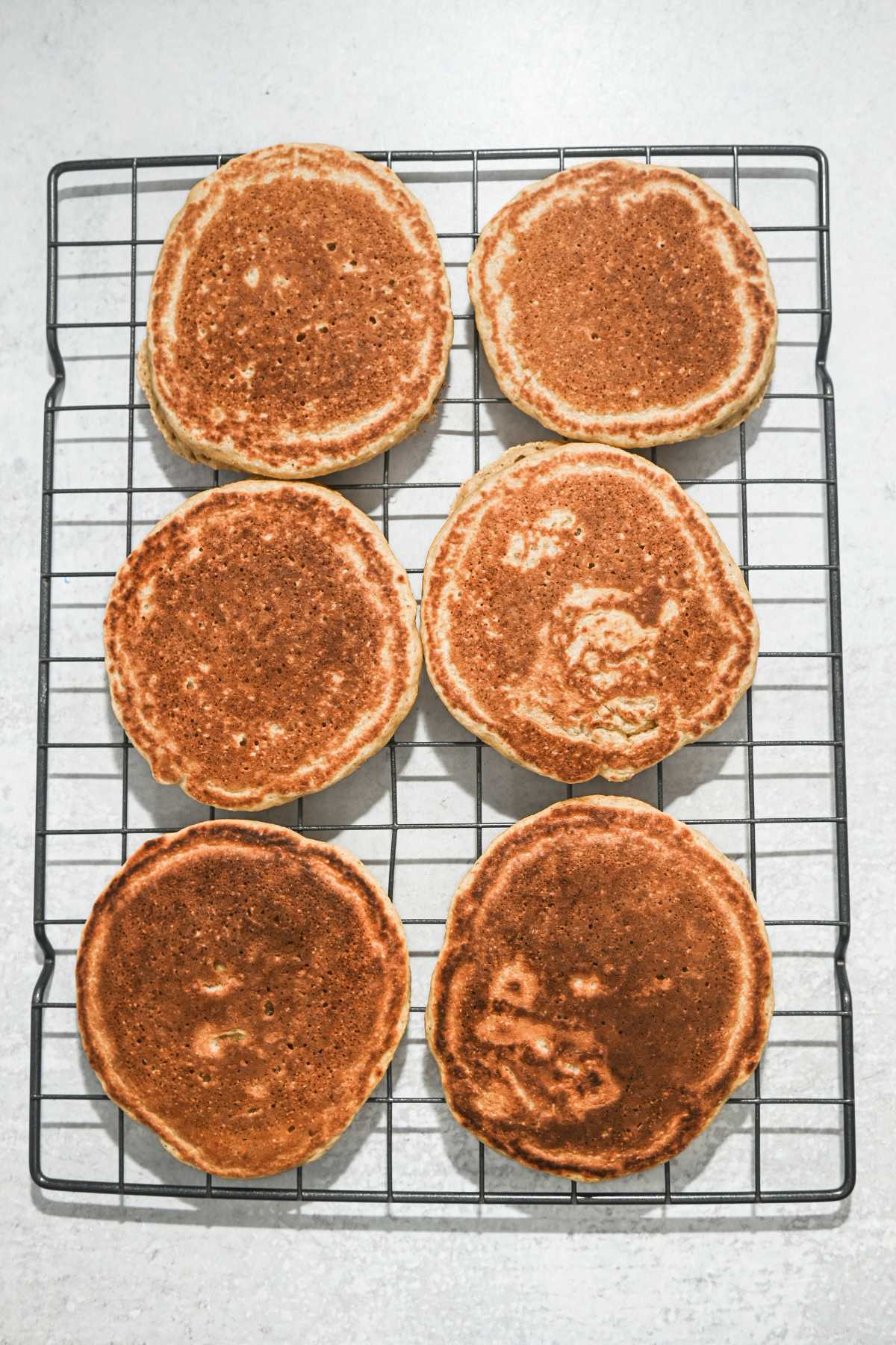 six oat flour pancakes on a cooling rack.