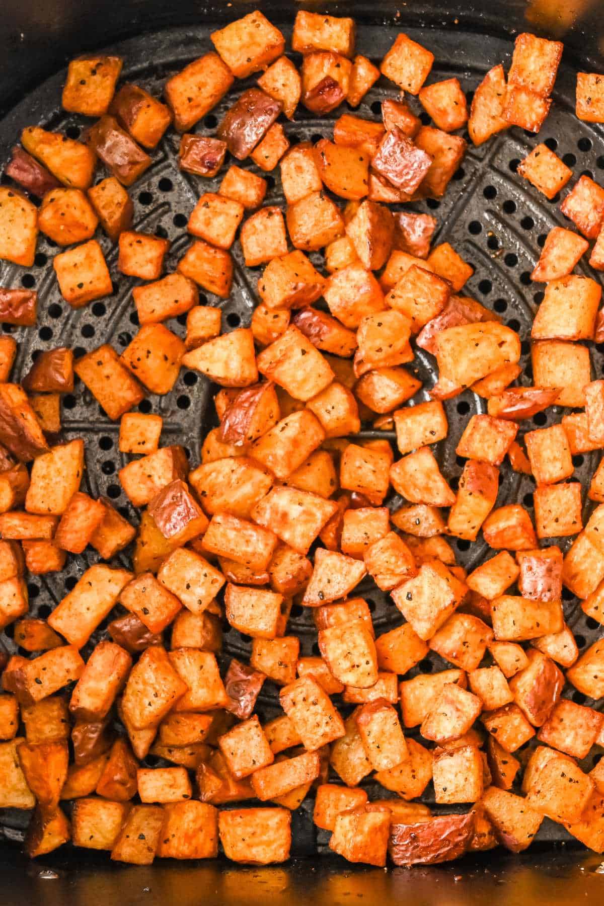 cooked red potatoes in a black air fryer basket.