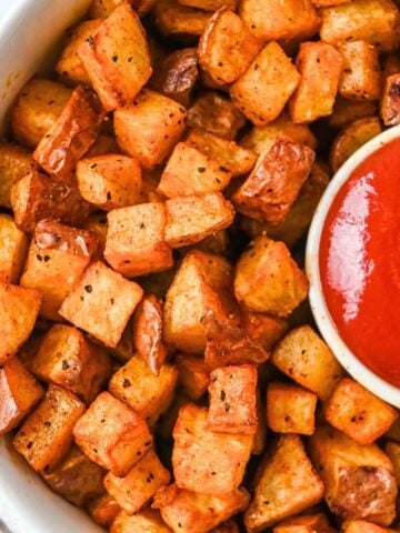 close up featured image of air fryer red potatoes in a white bowl with a side of ketchup.