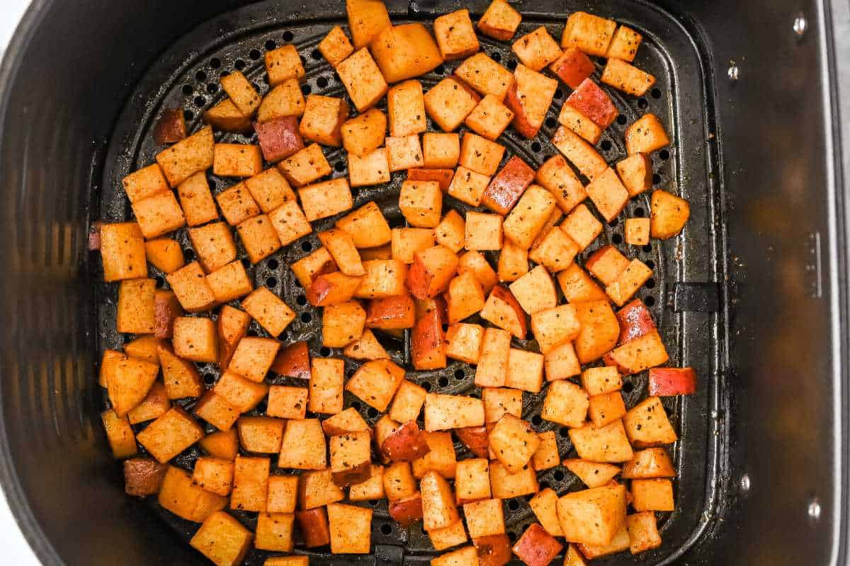 raw diced potatoes in air fryer basket.