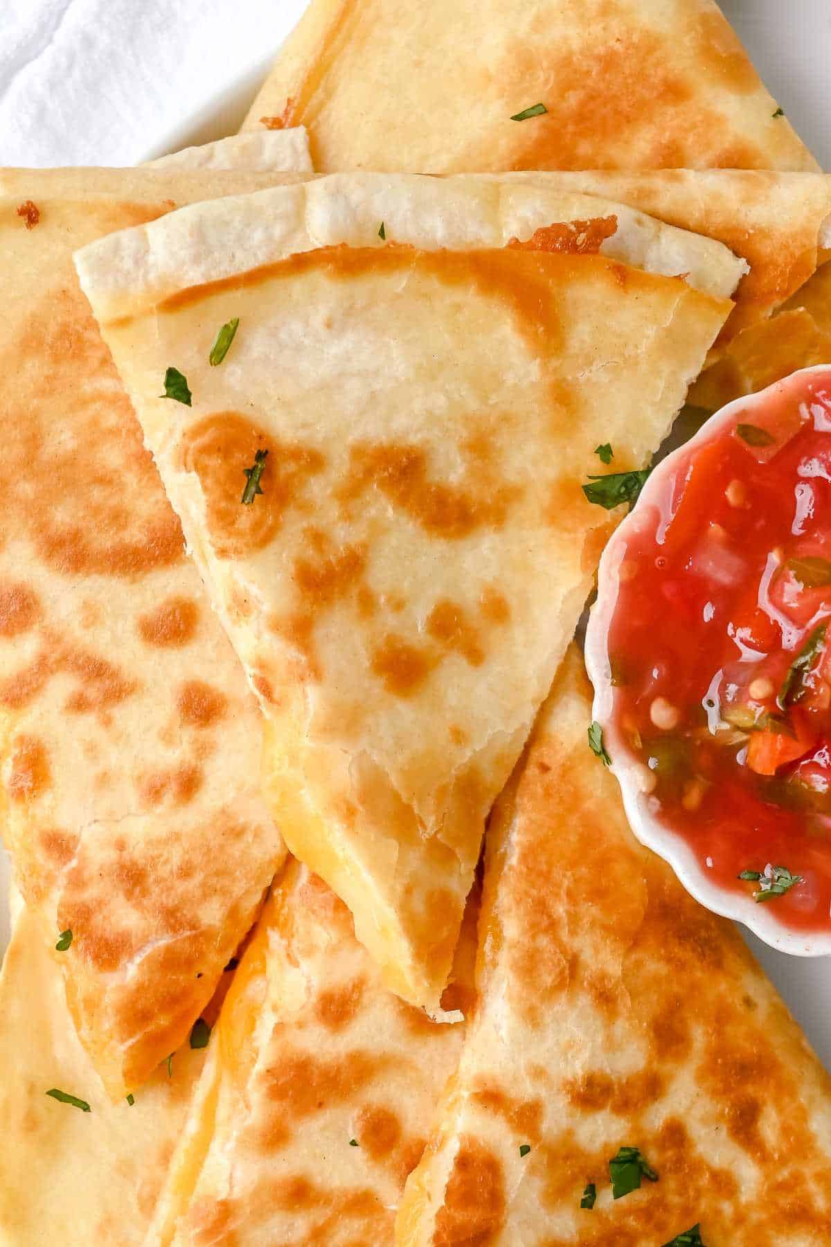 close up shot of cheese quesadilla next to salsa.