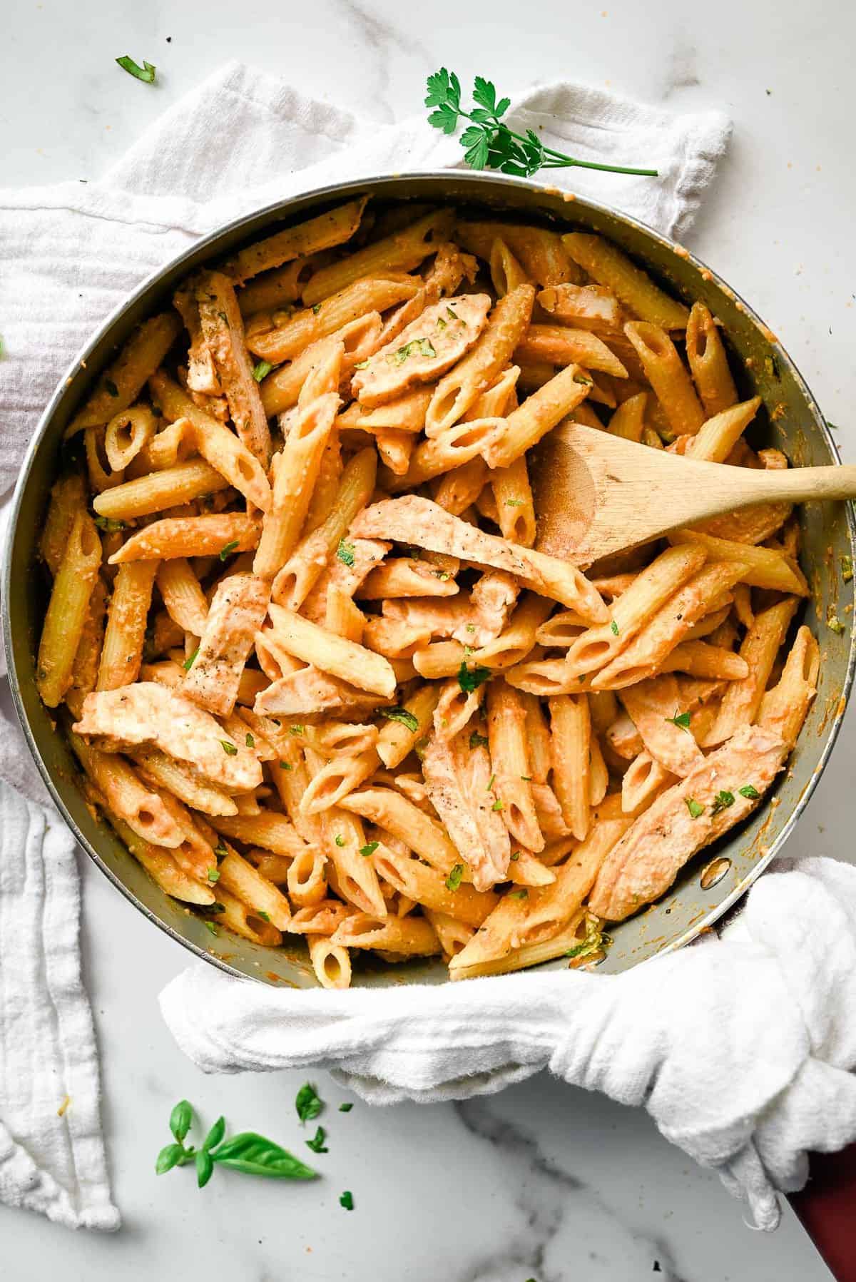 chicken penne alla vodka in a skillet on a white background.