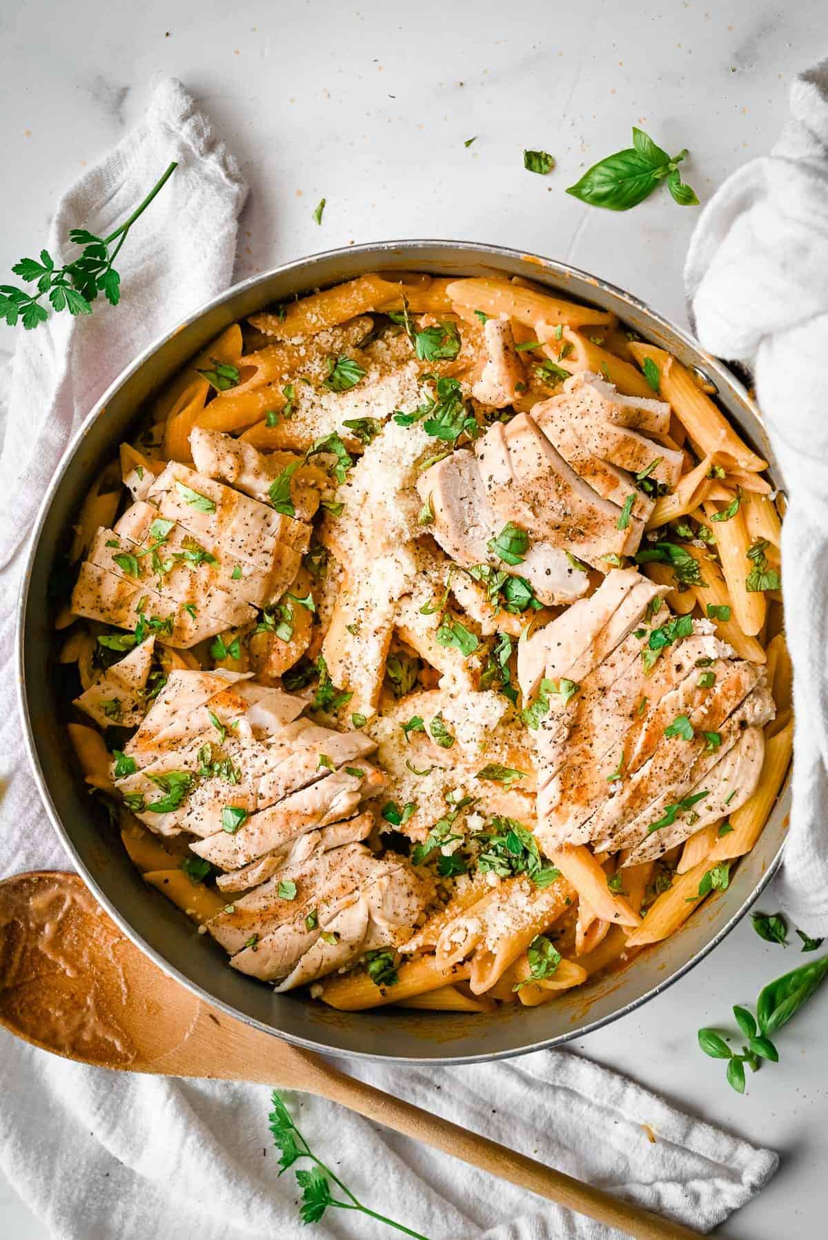healthy chicken penne alla vodka in a skillet topped with fresh herbs.