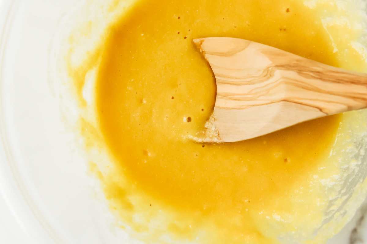 donut batter in a glass bowl with a wooden spoon.