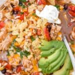 close up of 5-ingredient chicken tortilla soup topped with avocado slices and sour cream and with a silver spoon.