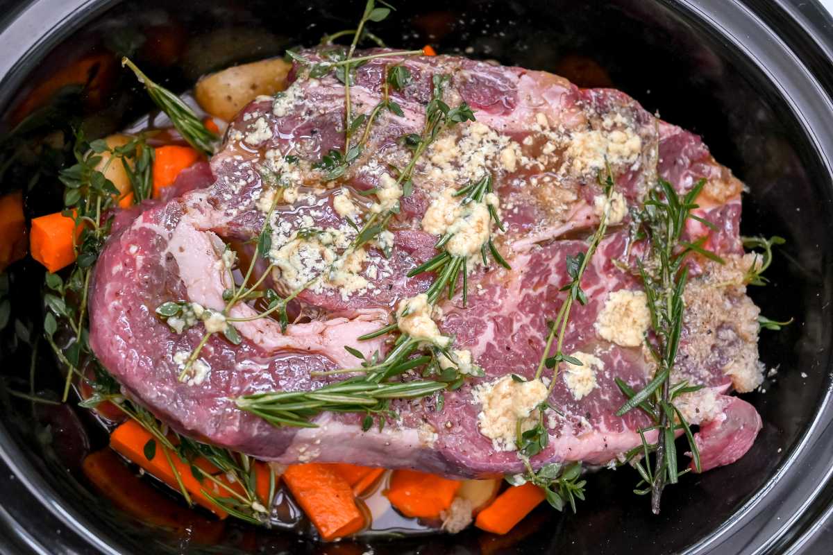 herbed meat on top of vegetables in a crock pot.