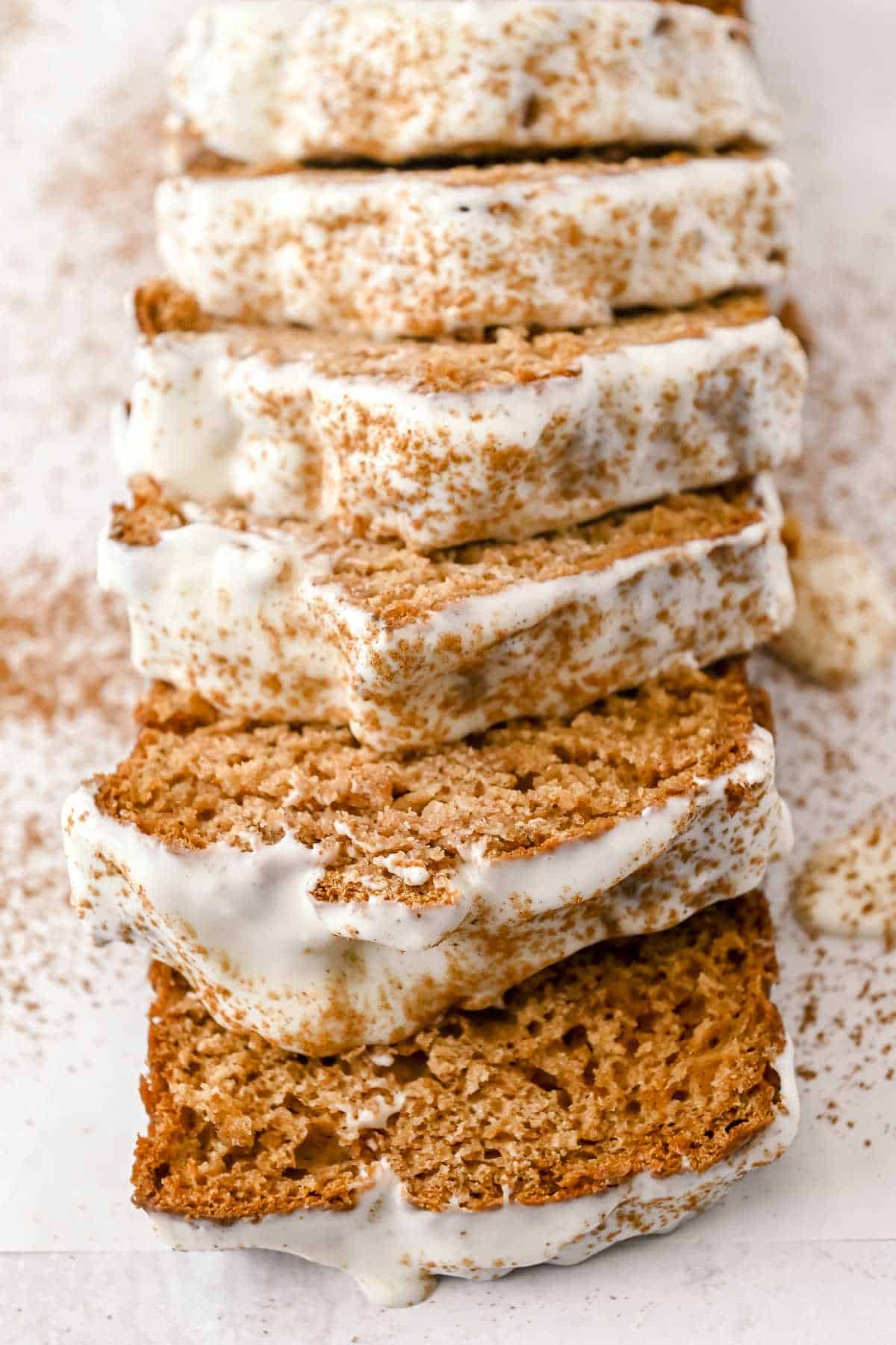 slices of gingerbread topped with cream cheese frosting lying flat on a white background.