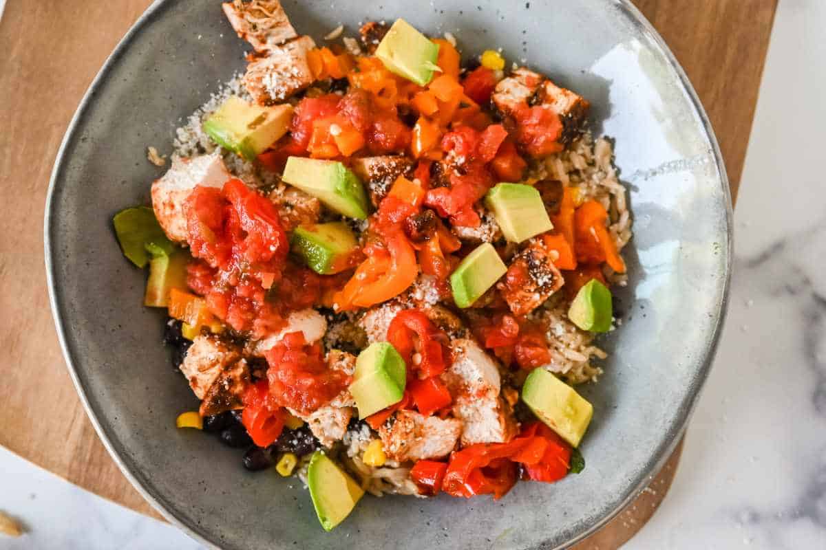 close up of southwest chicken bowl with veggie toppings in a gray bowl.