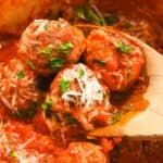 close up of eggless meatballs on a wooden spoon topped with parsley and parmesan cheese.