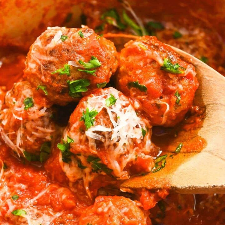 close up of eggless meatballs on a wooden spoon topped with parsley and parmesan cheese.