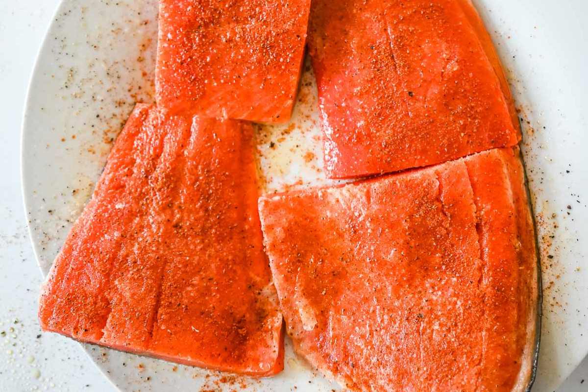 salmon on a white plate seasoned with Old Bay seasoning.
