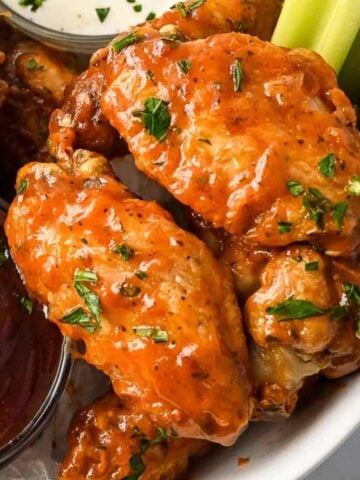 close up shot of two ninja foodi chicken wings topped with parsley.