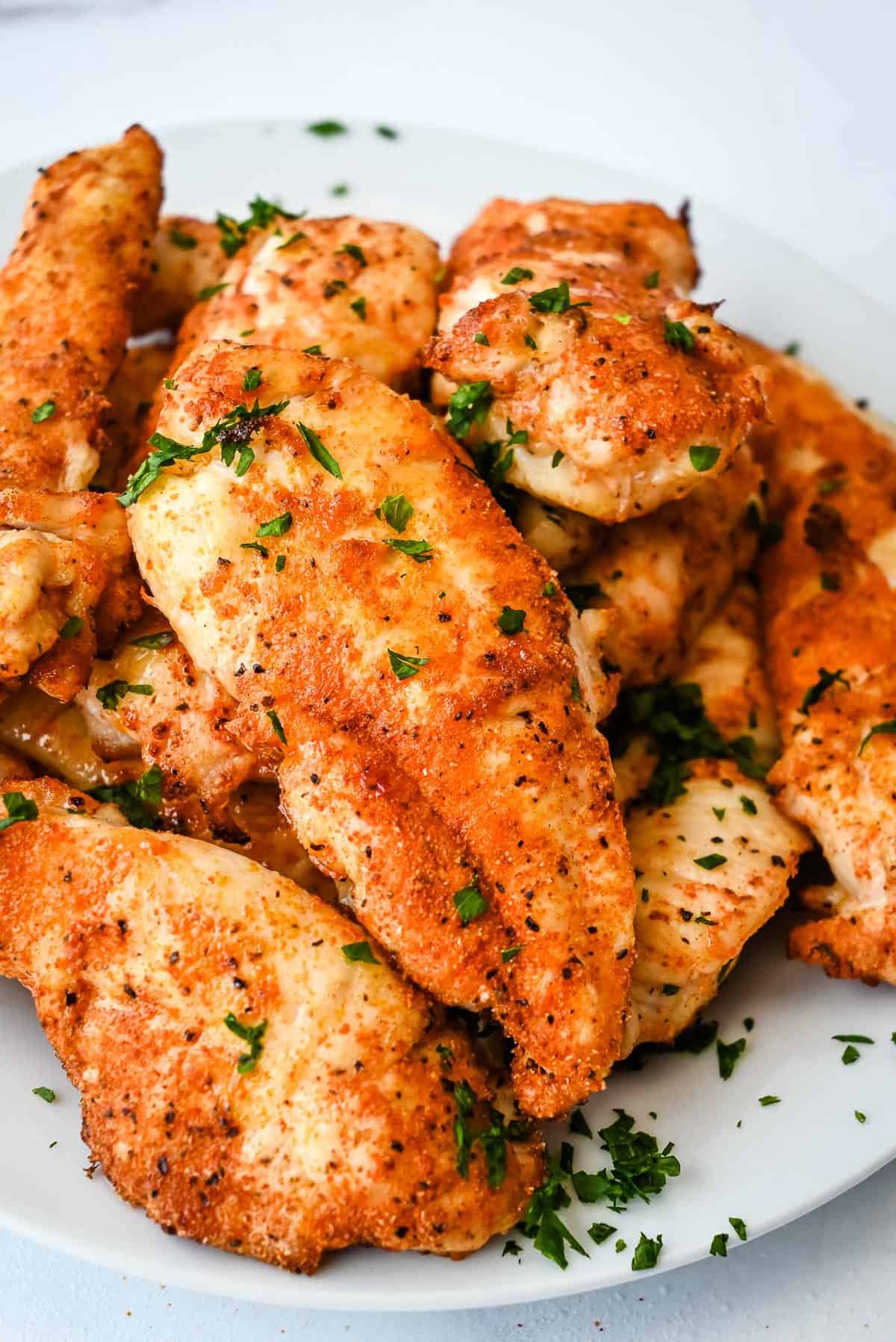 no breading air fryer chicken tenders in a white bowl topped with parsley.
