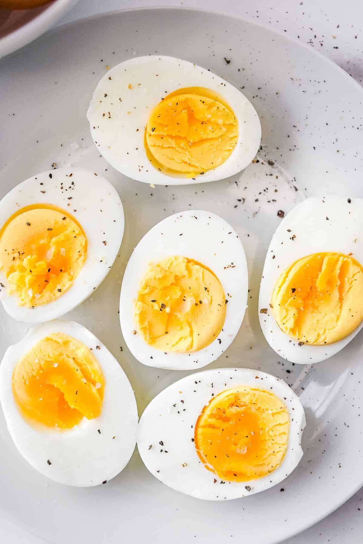 plate of ninja foodi hard boiled eggs cut in half, topped with pepper.