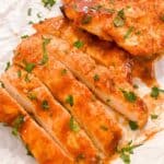 close up shot of sliced bbq chicken breast made in the air fryer topped with parsley.