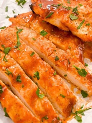 close up shot of sliced bbq chicken breast made in the air fryer topped with parsley.