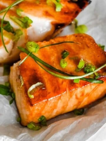 close up shot of soy marinated chilean sea bass topped with green onions.