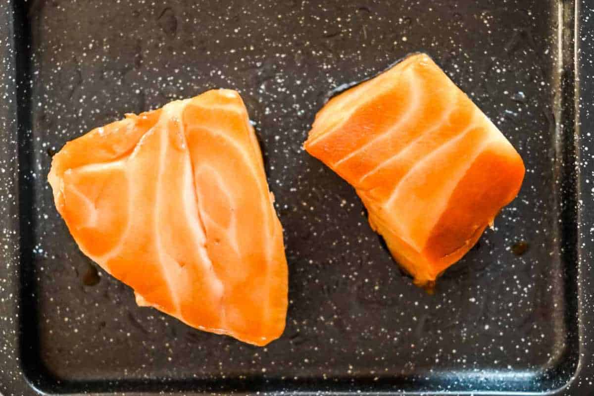 chilean sea bass on a black baking sheet.