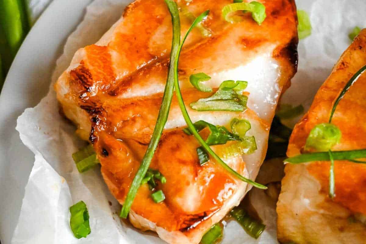 close up of chilean sea bass with green onions.