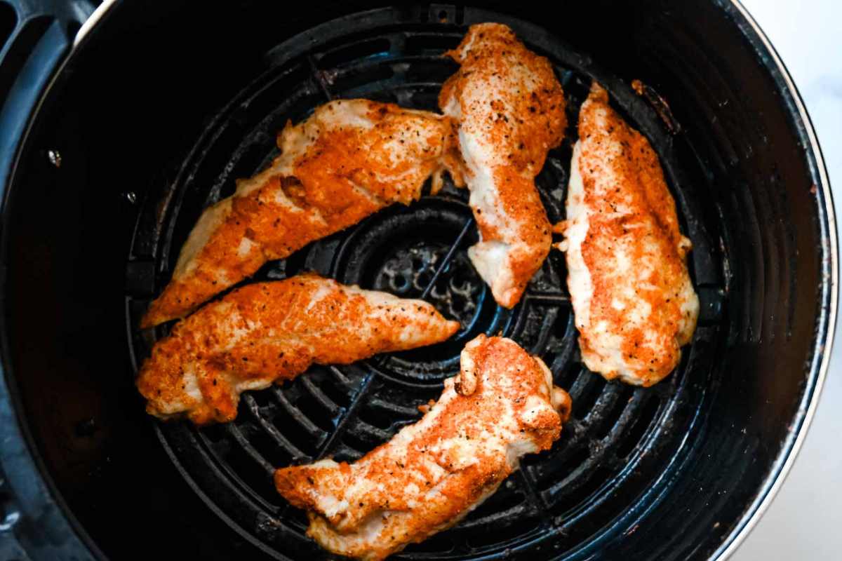 cooked chicken tenders in a black air fryer basket.