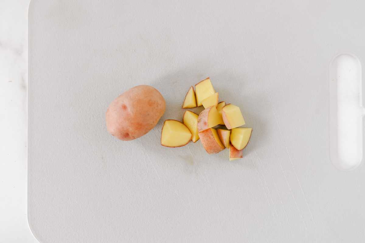 cutting small potatoes into diced cubes on a gray cutting board.