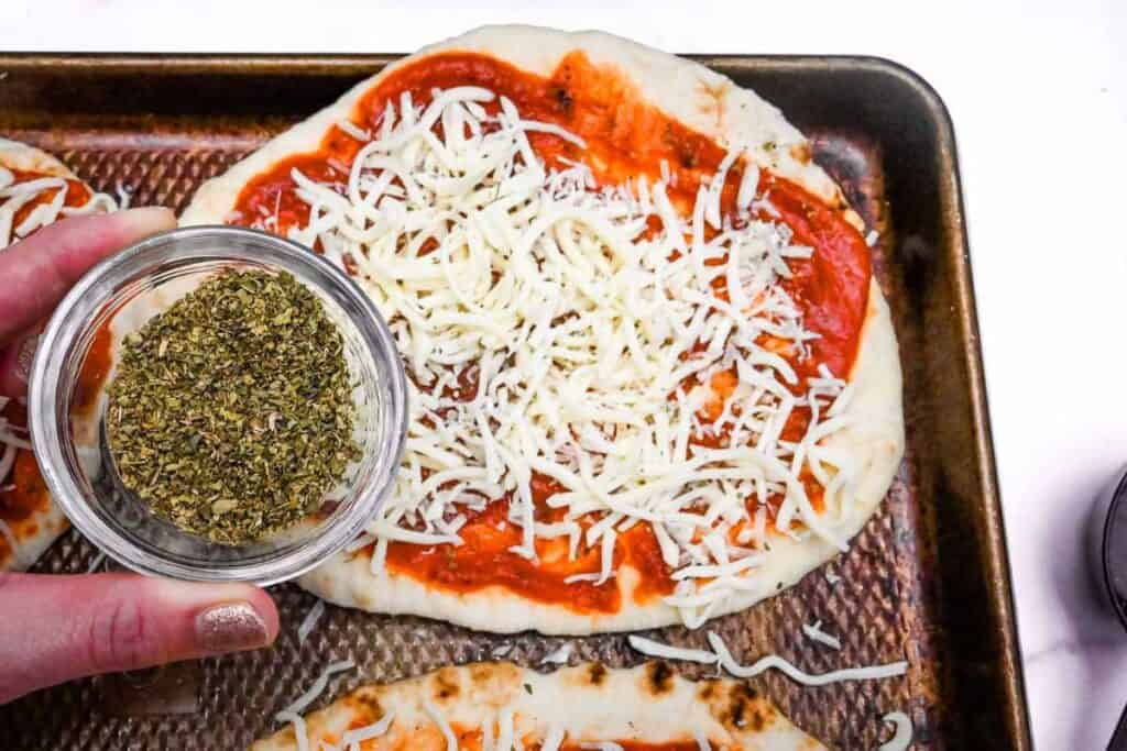 naan bread with seasoning on a sheet pan.