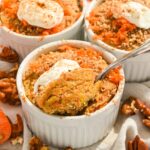 close up of carrot cake baked oatmeal with yogurt on top and a spoon inserted into the middle.