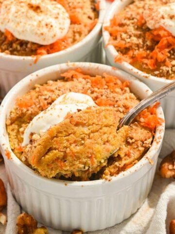 close up of carrot cake baked oatmeal with yogurt on top and a spoon inserted into the middle.
