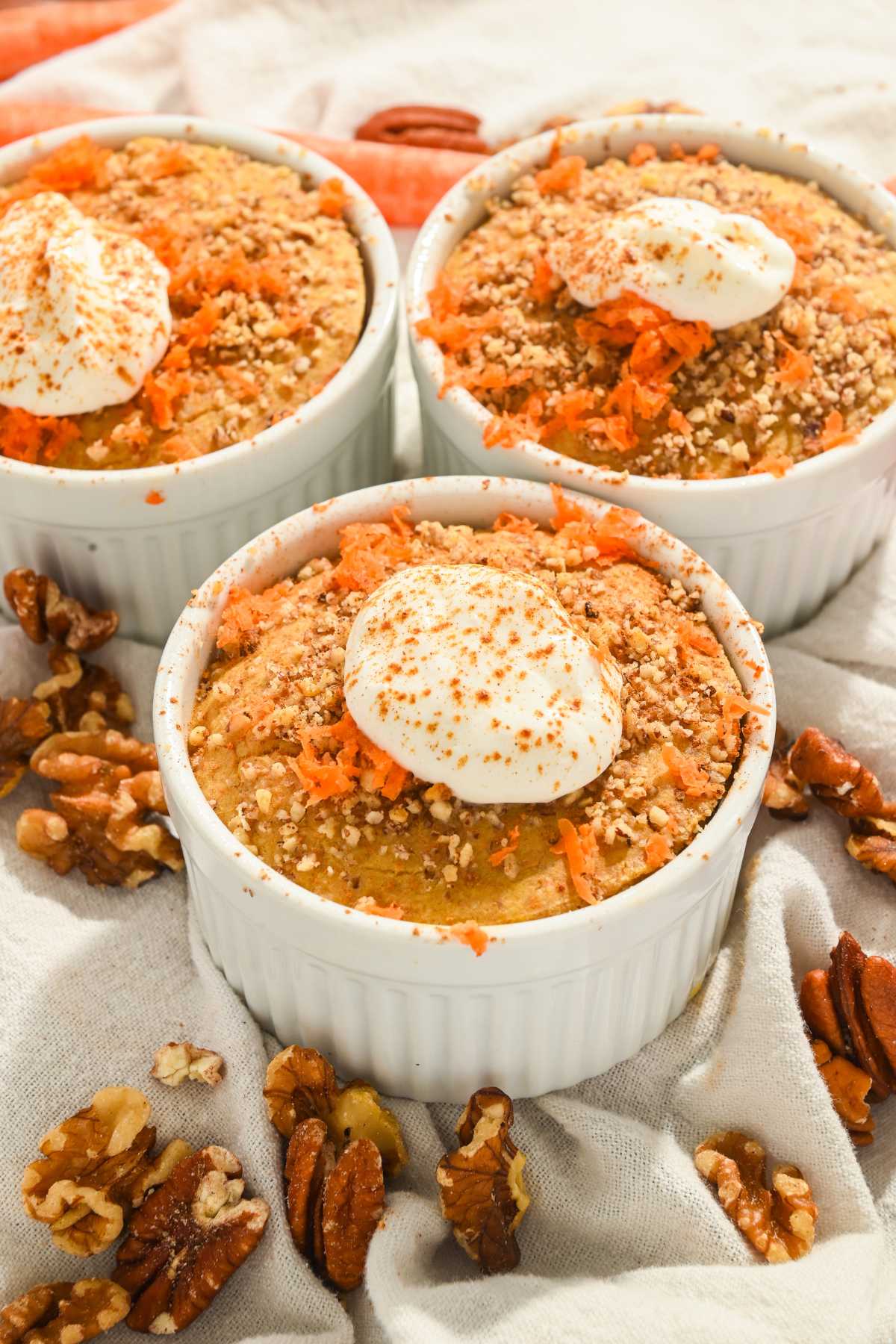 three ramekins containing carrot cake baked oatmeal with yogurt on top.