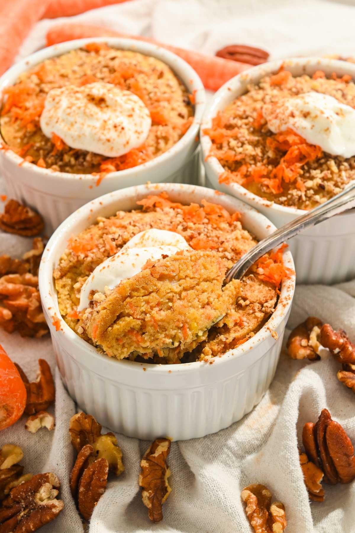 three ramekins containing carrot cake baked oatmeal with yogurt on top and a spoon inserted into the front one.