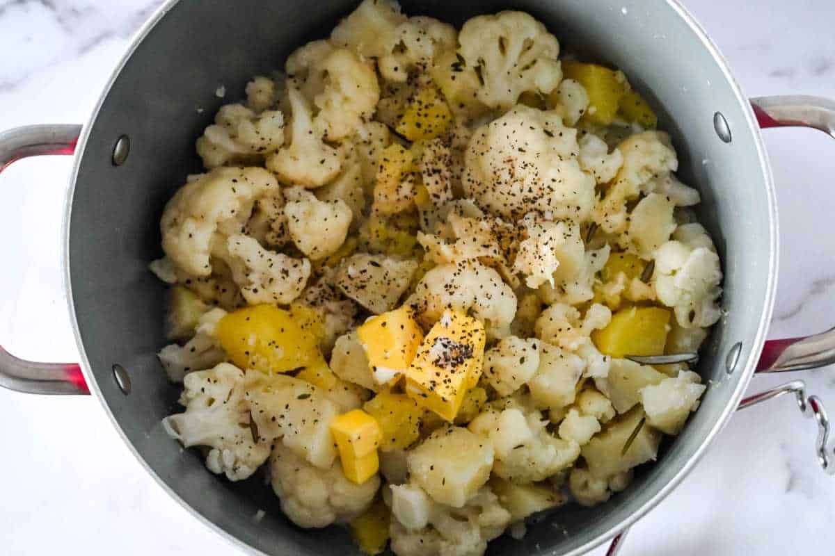 cooked cauliflower and potatoes in a pot with pepper on top.