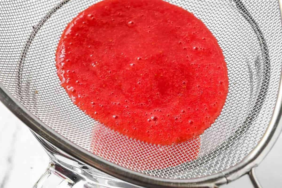 strawberry puree in a fine mesh sieve.