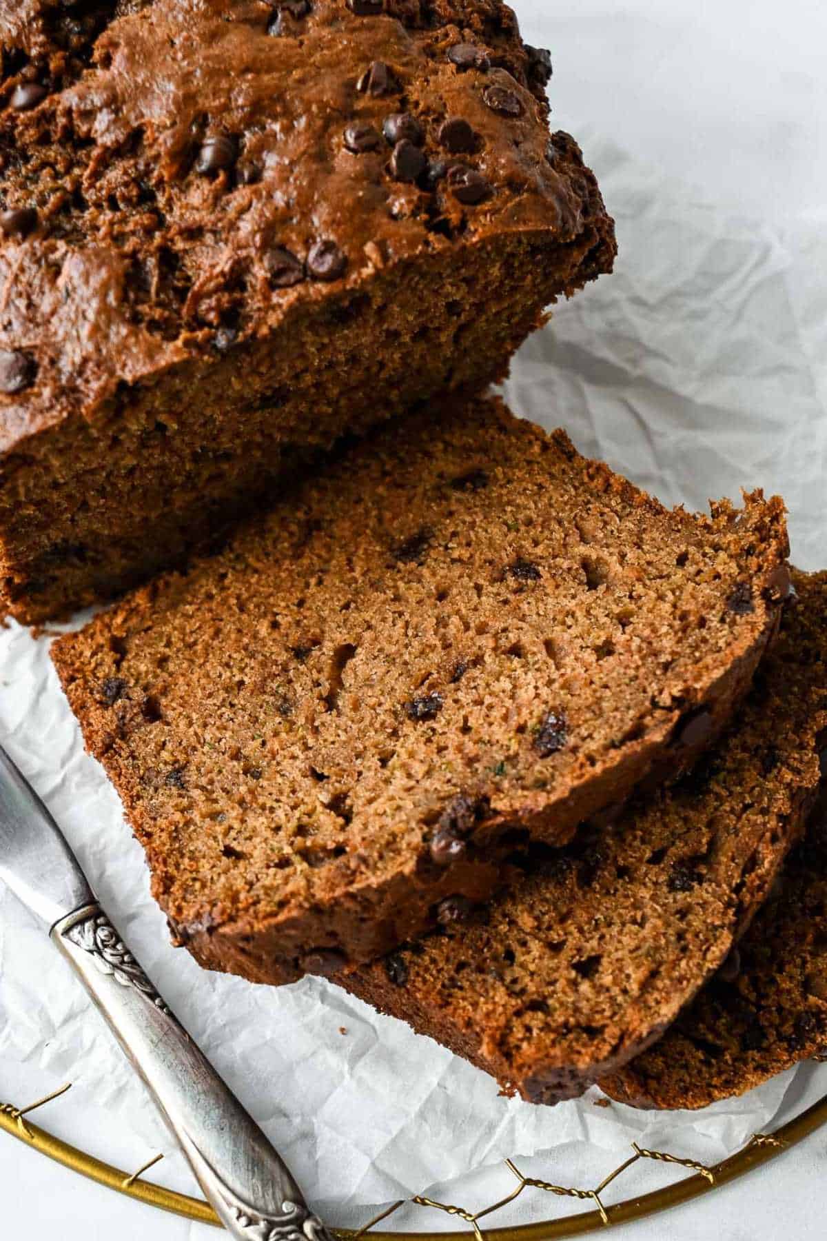 slices of healthy zucchini bread on parchment paper next to a knife.